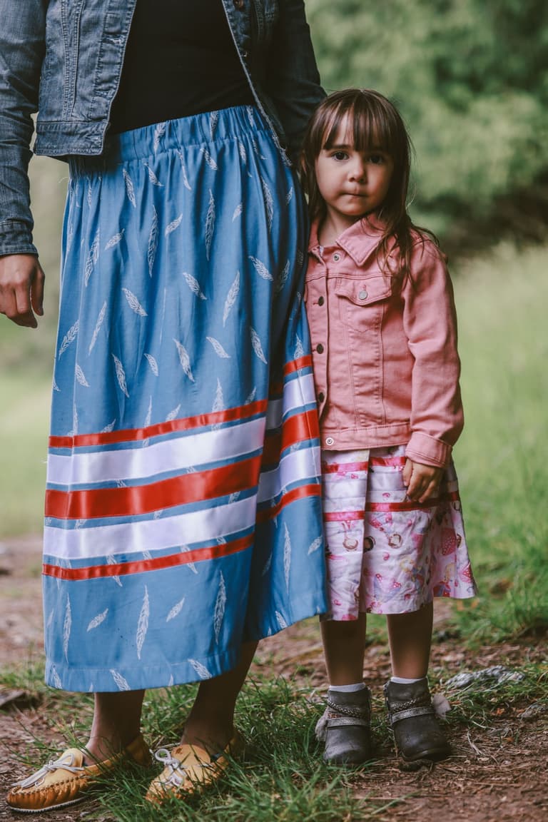 A child in a pink coat beside a blue ribbon skirt